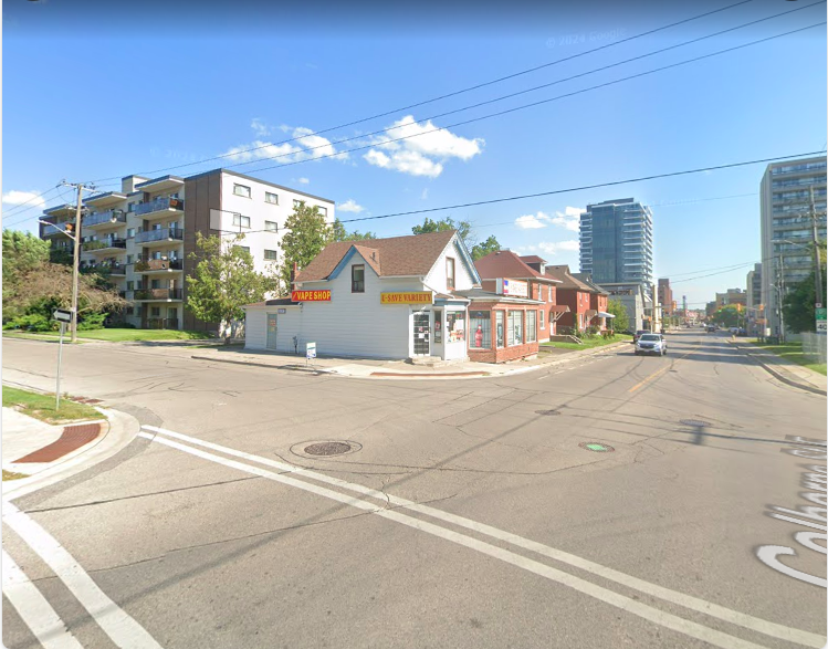 Wide street-corner view showing the Corner Vape Shop building and its red VAPE SHOP sign at Mary Street North and Colborne Street East in Oshawa